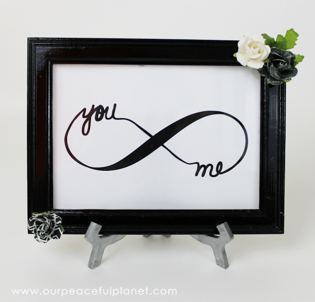  Free Couples Infinity DIY Bedroom Decor Looking for a quick and easy piece of DIY bedroom decor? Download our free couple’s infinity symbol, frame it and add some flowers. How’s that for easy? We took it even further and used an old frame we had and spiced it up a bit and also painted a easel. It turned out lovely and sits in our bedroom. The download comes in three sizes so you can choose and frame as desired or also mat it. DIY Bedroom Decor Supplies Free artwork download below (4×6 5×7 & 8×10) Frame Extras (flowers etc.) Glue gun Instructions Not that many are needed but I’ll show you what I did. I’m sure a lot of you will use a frame as it is. But I enjoyed upcycling one I had. Cut out your symbol size of choice. I used the 5×7. I found an old frame to upcycle. I spray painted it gloss black. Then I added my infinity symbol.I was going to make some mini spiral rose diy paper flowers but I had these in my craft supplies and they matched my bedroom and the frame so I decided to use them. I glued my flowers on opposite corners of my frame. I also had an old tripod. Since I wanted to set my frame on a shelf I used it.I wanted it to be silver though so I spray painted it.