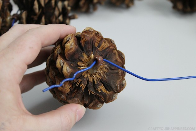 Learn how to make a pinecone wreath in 30 minutes! You can decorate the base wreath however you wish. We used a big red bow. Plus it's an upcycle project!