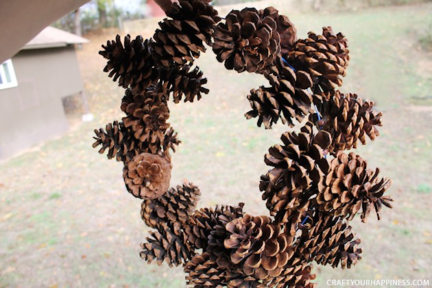 Learn how to make a pinecone wreath in 30 minutes! You can decorate the base wreath however you wish. We used a big red bow. Plus it's an upcycle project!