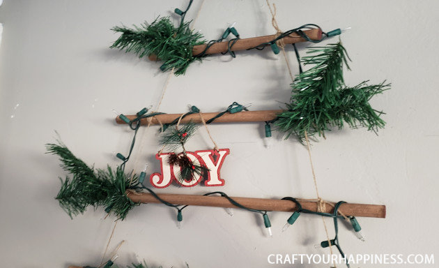 This easy DIY hanging wall Christmas tree made from dowels (or branches) is perfect if you're on a budget or you have very little space for a normal tree. 