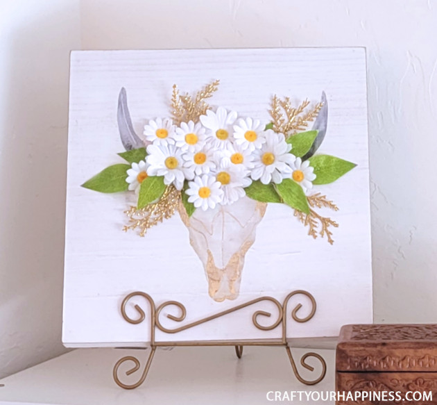 If you have old artwork that no longer fits your home decor here's a quick fun way to update it with a simple 3D painting makeover! Some artificial flowers and a hot glue gun is all we used!